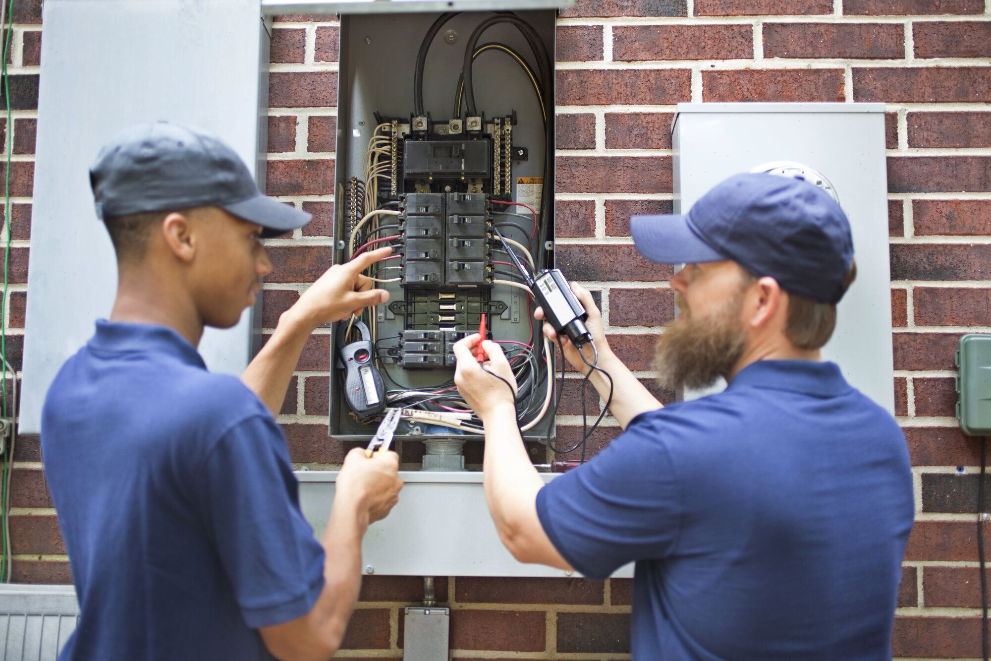Two Pro Max Electrical technicians diagnosing a breaker panel in West Houston