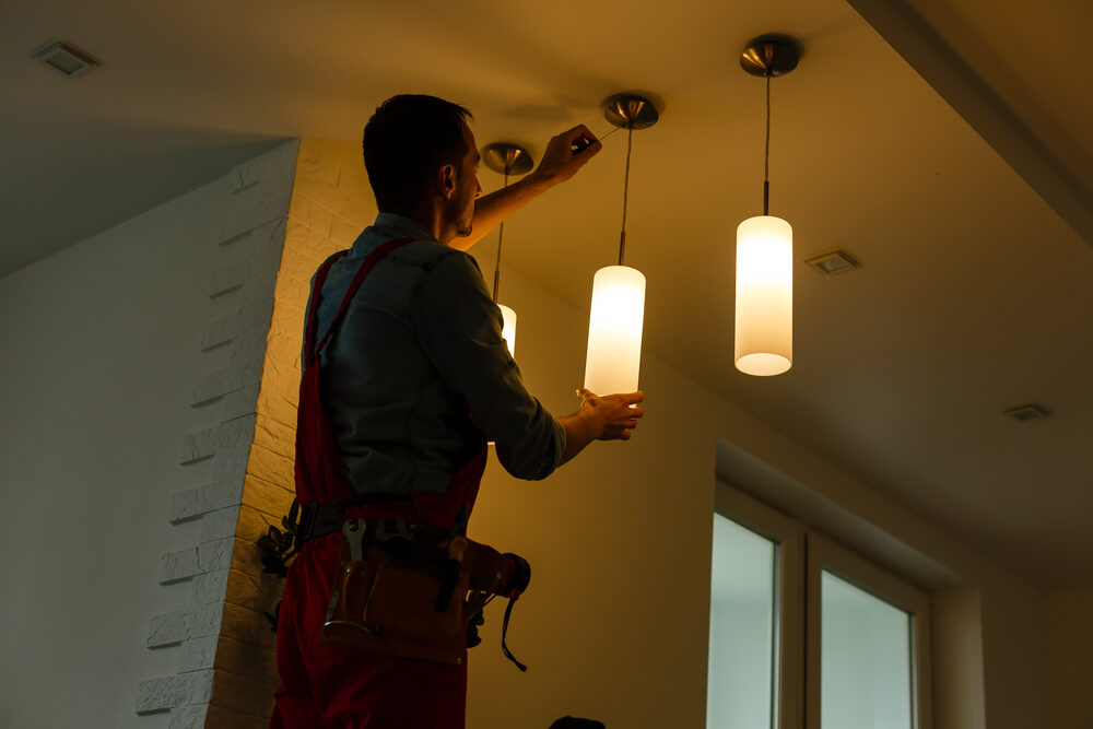 Electrician installing pendant lighting indoors